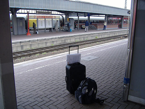 dos maletas en una estación de tren al fondo se ve el tren