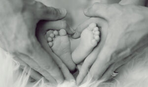 Los pies de un bebé entre las manos de sus padres.