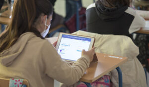 Una alumna en clase con mascarilla para protegerse del Covid-19 y ante una tableta digital.