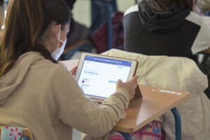 Una alumna en clase con mascarilla para protegerse del Covid-19 y ante una tableta digital.