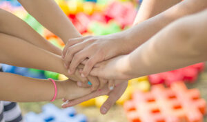 Varios niños entrelazan sus manos en una actividad colaborativa.