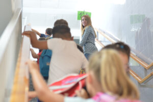 Niños de Primaria se dirigen a su aula bajo la mirada de una trabajadora del centro escolar.