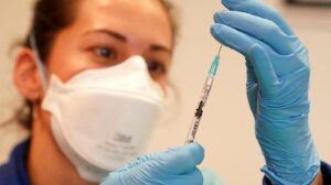 Una profesional sanitaria se dispone a administrar una vacuna.