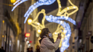 Una mujer con mascarilla en una calle con iluminación navideña (Foto: EFE).